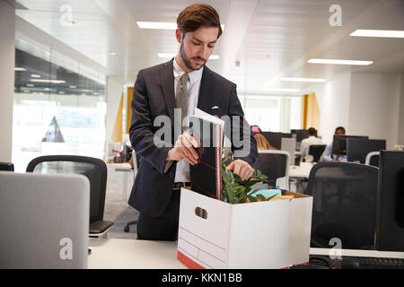 Sparò dipendente di sesso maschile scatola di imballaggio dei beni in un ufficio Foto Stock