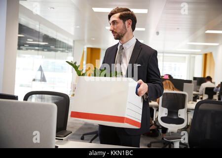 Sparò dipendente di sesso maschile della scatola di contenimento di oggetti personali in un ufficio Foto Stock