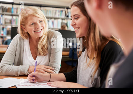 Insegnante femminile lavora con studenti di college in libreria Foto Stock