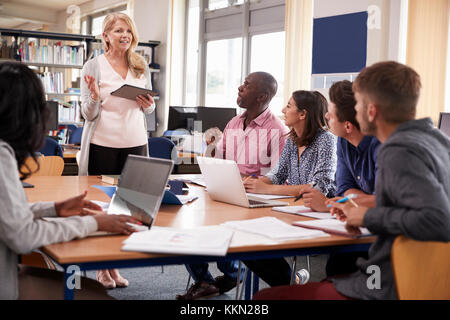 Tutore con gruppo di coppia College gli studenti che lavorano in biblioteca Foto Stock