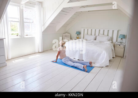 La donna a casa la mattina partenza con esercizi di yoga in camera da letto Foto Stock