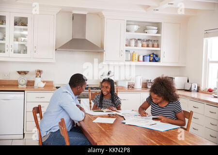 Aiutando il padre di due figlie seduta a tavola facendo i compiti di scuola Foto Stock