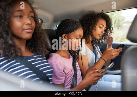 Figli adolescenti utilizzando dispositivi digitali su Famiglia Viaggio su strada Foto Stock