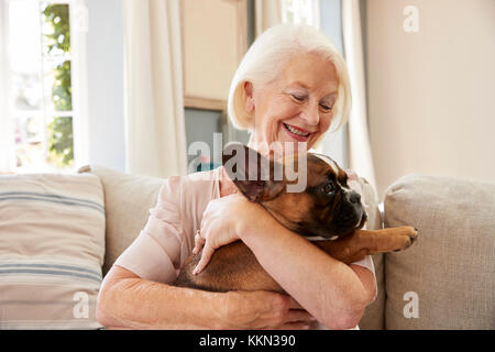 Senior donna seduta sul divano di casa con Pet bulldog francese Foto Stock