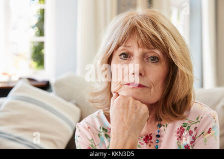 Ritratto di donna Senior sul divano che soffrono di depressione Foto Stock