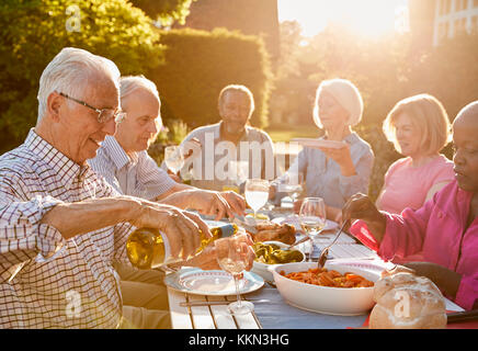 Gruppo di alti amici gustando una cena all'aperto parte a casa Foto Stock