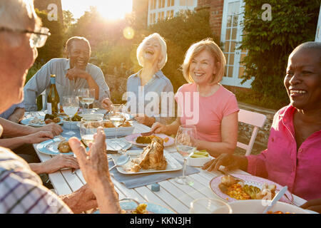 Gruppo di alti amici gustando una cena all'aperto parte a casa Foto Stock