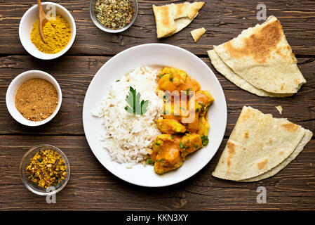 Delizioso pollo al curry con riso su sfondo di legno. top view, laici piatta Foto Stock