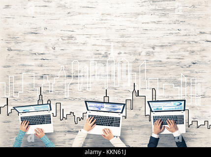 Un gruppo di tre persone con i dispositivi in mani lavorando insieme come simbolo del collegamento in rete e comunicazione Foto Stock