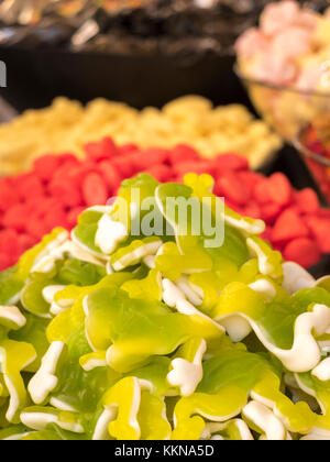 Variato candy ammassi in primo piano frutto gum caramelle gommose, verde e bianco su sfondo rosso e giallo caramelle di zucchero. Foto Stock