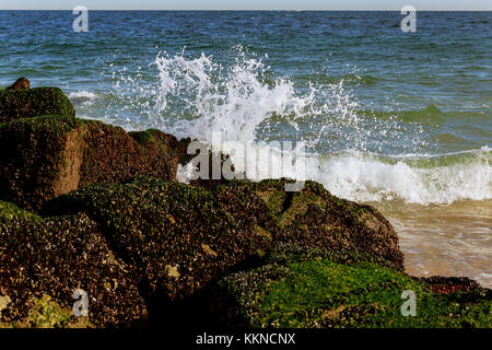 Grandi onde che si infrangono sulla riva con schiuma di mare Costa dell'oceano onda di pietre Foto Stock