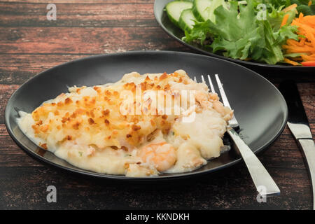 Torta di pesce condito con purè di patate e insalata di contorno Foto Stock
