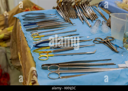 Focus al scaples,gli strumenti tra cui il bisturi, pinze e pinzette a molla disposti su una tavola per un intervento chirurgico di preparazione chirurgica per strumenti di chirurgia Foto Stock