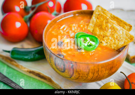 Piccante e speziato fatto fresco peperoncino Messicano zuppa su sfondo rustico Foto Stock