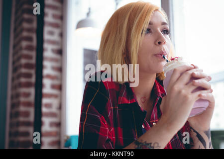 Donna alla moda che beve latte Foto Stock
