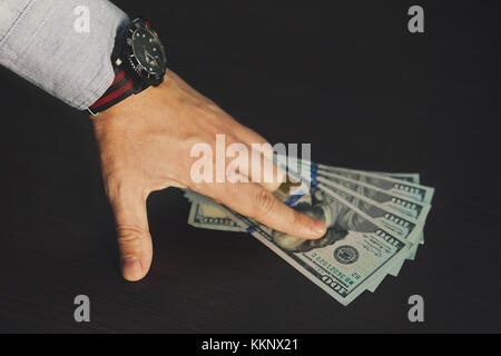 Dollari americani. corrompere e concetto corrotto. Un uomo punti un dito al 500 dollari bollette per un centinaio di dollari su un colore marrone scuro tabella Foto Stock