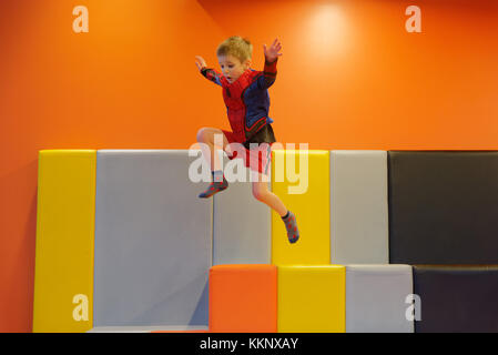 Un piccolo ragazzo (5 anni) di saltare in un imbottito per area di gioco Foto Stock