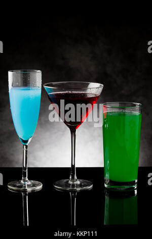 Foto di tre cocktail in vetro nero con contatore grigio sfondo illuminato Foto Stock