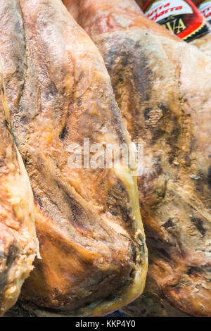 Tutta la gambe di cured prosciutto iberico appeso nel reparto macelleria di un supermercato spagnolo. novembre 2017. Foto Stock