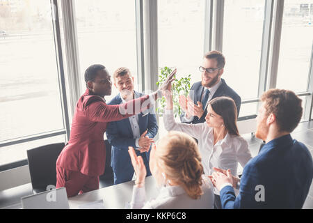 La gente di affari dando ad alta cinque mentre i loro colleghi guardano Foto Stock