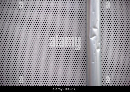 Dettaglio di un ammaccato grondaia pioggia su una piastra metallica traforata, close-up Foto Stock