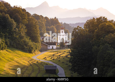 L'iconica Chiesa di Wamberg, con il Monte Alpspitze e Zugspitze sullo sfondo. Wamberg, Garmisch-Partenkirchen, Baviera, Germania Foto Stock