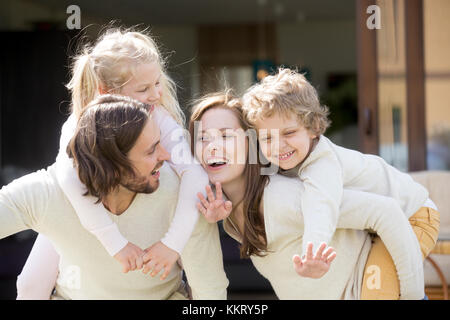 Sorridenti genitori piggybacking figlio e figlia, famiglia leis Foto Stock