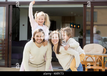 La famiglia felice avendo divertimento sulla terrazza della casa guardando la fotocamera Foto Stock