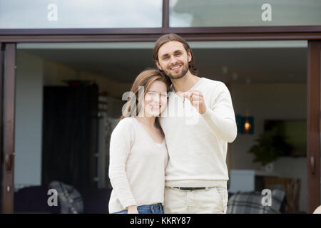 Coppia felice homeowners tenendo premuto i tasti in piedi contro il nuovo proprio ho Foto Stock
