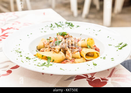 Otranto città, regione Puglia, il sud dell'Italia. tradizionale pasta paccheri con pesce spada, servita con pomodoro, prezzemolo, olio d'oliva. La luce diurna, restaur reale Foto Stock