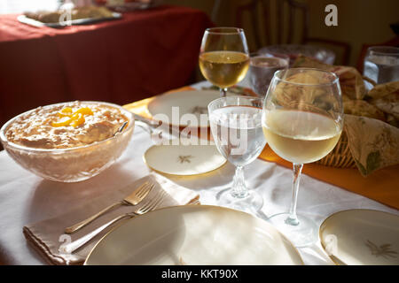 Tavolo da pranzo insieme per la cena di ringraziamento con argenteria, le placche vuote, vino bianco freddo in bicchieri e un assortimento di cibo in una vista ravvicinata in ambienti interni Foto Stock