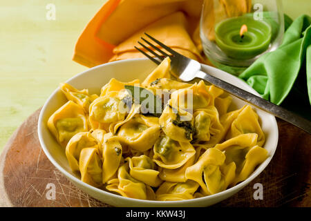 Deliziosi piatti della cucina italiana tortellini freschi con burro e salvia con sfondo verde Foto Stock