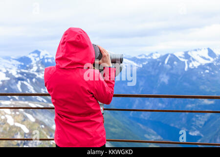Turismo Viaggi e vacanze. donna cerca attraverso visite binocolo telescopio turistica, si affaccia il Geirangerfjord e montagne paesaggio dal d Foto Stock