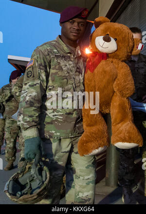 Fort Bragg, North Carolina, Stati Uniti. 1 dicembre 2017. 1 dicembre 2017 - FORT BRAGG, N.C., USA - Paracadutista dell'esercito statunitense, Sgt. Wisdom Koduah, assegnato al 3rd Battalion, 319th Airborne Field Artillery Regiment, 1st Brigade Combat Team, 82nd Airborne Division, dona un grosso orsacchiotto alla Green Ramp sul Pope Army Airfield, venerdì, al 20th Annual Randy Oler Memorial Operation Toy Drop. L'operazione aviotrasportata, ospitata dallo U.S. Army Civil Affairs & Psychological Operations Command (Airborne), è la più grande operazione aerea combinata al mondo con paracadutisti provenienti da nove nazioni alleate partecipanti. T Foto Stock