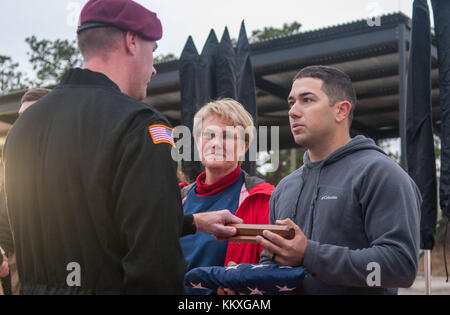 Fort Bragg, North Carolina, Stati Uniti. 2 dicembre 2017. 2 dicembre 2017 - FORT BRAGG, N.C., USA - Pam Oler e suo figlio, Andrew Oler, sono presentati con una bandiera americana da un membro della squadra dimostrativa dei Golden Knights dell'esercito degli Stati Uniti presso la Sicily Drop zone al 20th Annual Randy Oler Memorial Operation Toy Drop, ospitato dallo U.S. Army Civil Affairs & Psychological Operations Command (Airborne). L'evento annuale, presentato come la più grande operazione aerea combinata al mondo con paracadutisti provenienti da nove nazioni alleate, consente ai paracadutisti di aiutare i bambini nelle comunità che circondano Fort Bragg Foto Stock