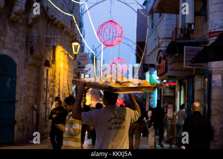 Betlemme, west bank. 2 dicembre, 2017. L'uomo porta fresca pane pita come Betlemme illumina con luci festose in previsione della grande quantità di turisti e pellegrini che arrivano per le vacanze di Natale. Credito: gabi berger/alamy live news Foto Stock