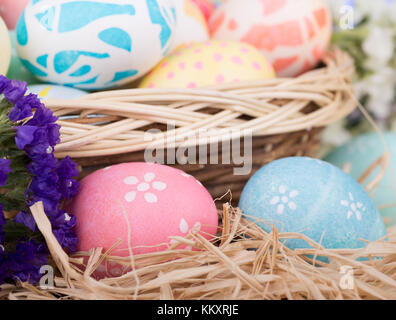 Composizione creativa di due candele bianche e tre uova piccole decorate  con macchie dorate all'interno del nido sul tappetino marrone chiaro, fatte  a mano dall'acqua Foto stock - Alamy