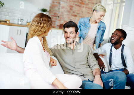 Due felici coppie giovani parlare durante la raccolta a casa il fine settimana Foto Stock