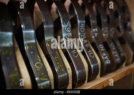 Fila di pezzi metallici per suole sul ripiano di legno in officina cobbler Foto Stock