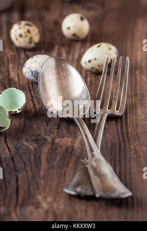 Pasqua messa in tavola con uova di quaglia e argenteria vintage sul vecchio tavolo in legno Foto Stock