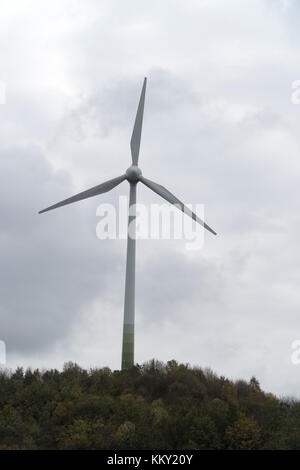 Turbina eolica per la generazione di energia elettrica su una collina boscosa Foto Stock