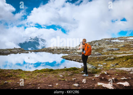 Fotografo di natura turistico con fotocamera germogli mentre permanente sulla cima della montagna. Bellissima natura della Norvegia Foto Stock