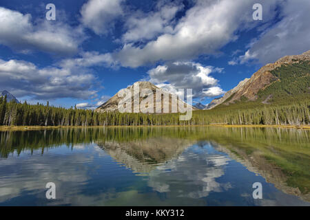 Big Blue sky, montagne e belle nuvole riflettono ancora in acque di buller pond in spray valley Provincial Park in Alberta, Canada. orizzontale 1 Foto Stock