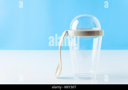 Vuoto in plastica monouso frullato tazza con coperchio trasparente. contenitore per il freddo, bevanda calda, succhi di frutta fresca, caffè e tè. sul tavolo bianco e blu backgro Foto Stock