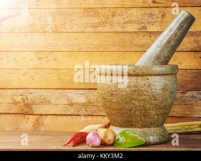 Mortaio e pestello e pasta di spezie di thai popolare cibo curry rosso sul tavolo di legno Foto Stock