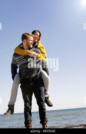 Giovane, mar baltico, spiaggia a piedi, piggyback, Foto Stock