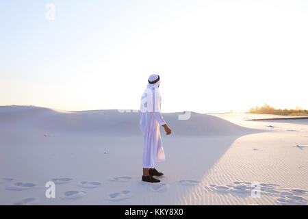 Bel giovane musulmano lungo la guida bottomless deserto e guardando verso il tramonto, ammirando la bellezza della natura nelle calde notti chiare. attraente smil musulmano