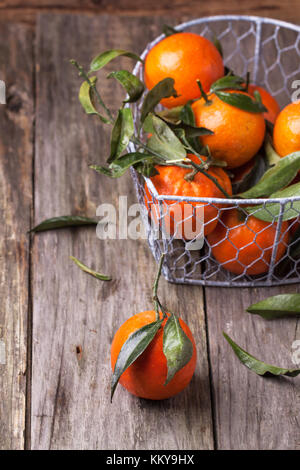 Tangerini con foglie sul vecchio sfondo di legno. Vedere serie Foto Stock