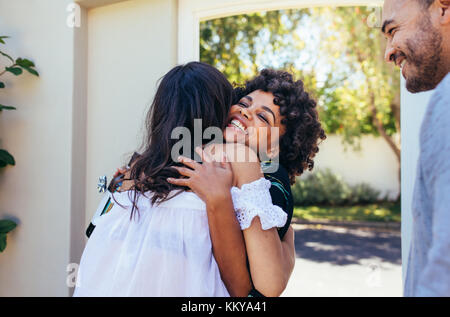 Donna africana saluto amico femmina per avere una nuova casa. Sorridente giovane donna congratulandosi con il suo amico. Paio accogliere amico per l inaugurazione della casa nuova p Foto Stock