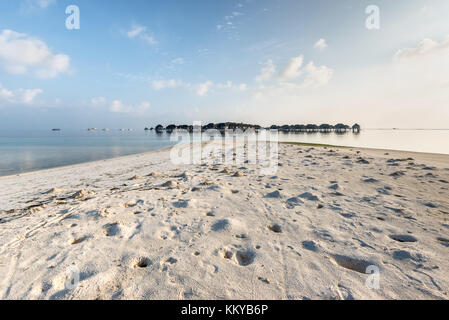 Maldive water bungalow sull'acqua dell'oceano paesaggio. granchi fori sulla spiaggia di sabbia in primo piano. Foto Stock